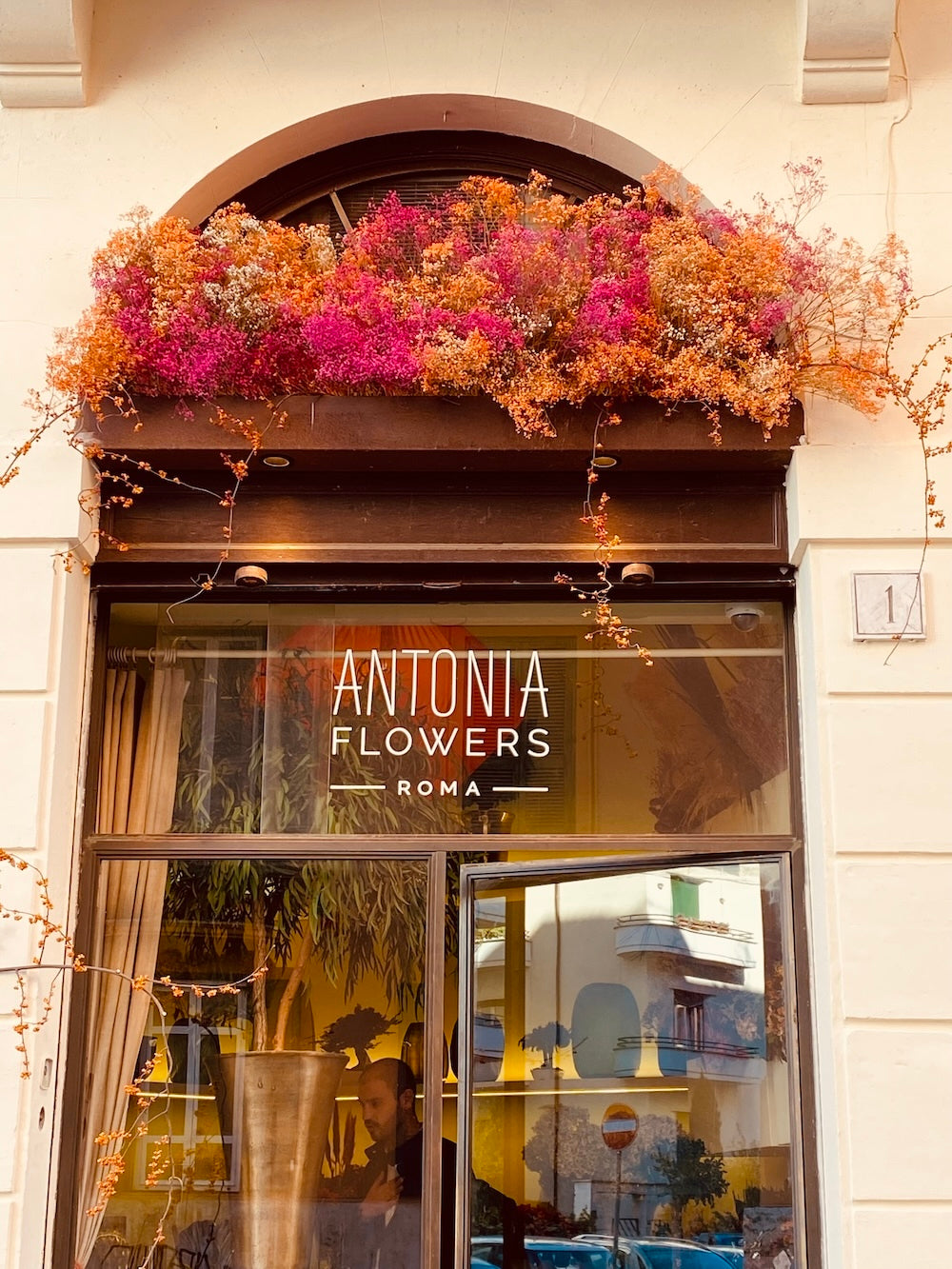 Facciata dell’atelier Antonia Flowers Roma con installazione floreale nei toni rosa e arancio