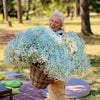 Fiorista con grande cesto di gypsophila bianca durante un allestimento all’aperto