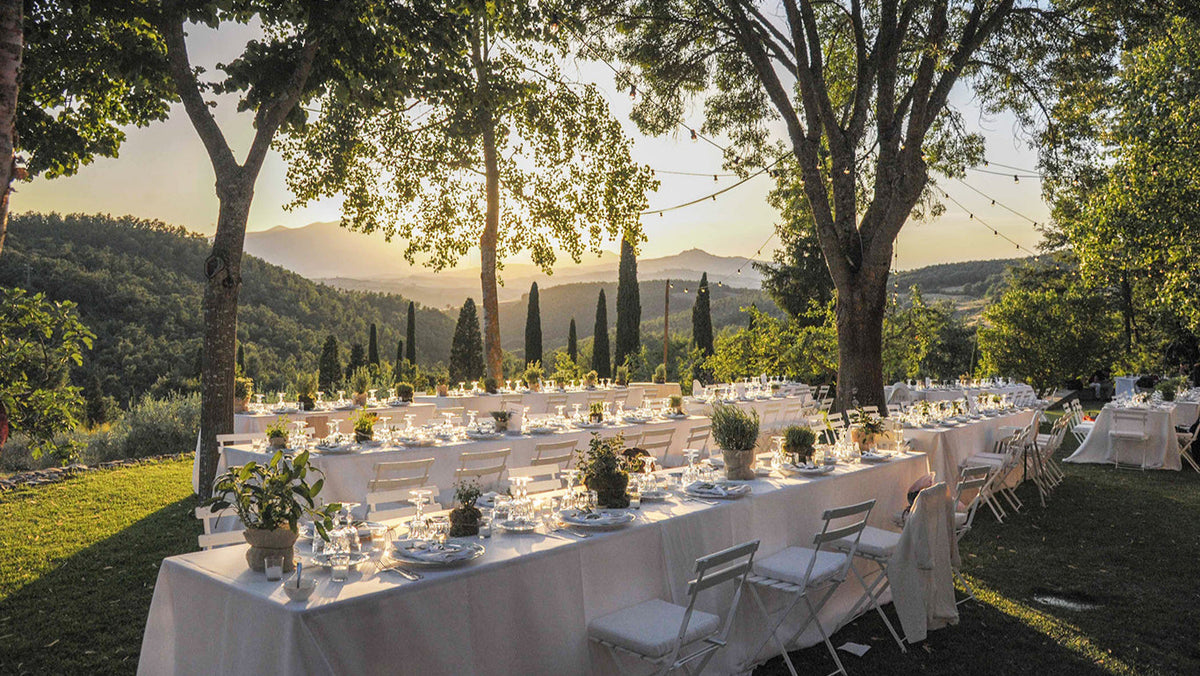 llestimento di tavoli per evento all’aperto con decorazioni floreali immerse nel paesaggio collinare